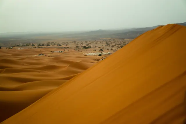 Sahara dune ridge with a desert settlement in the distance